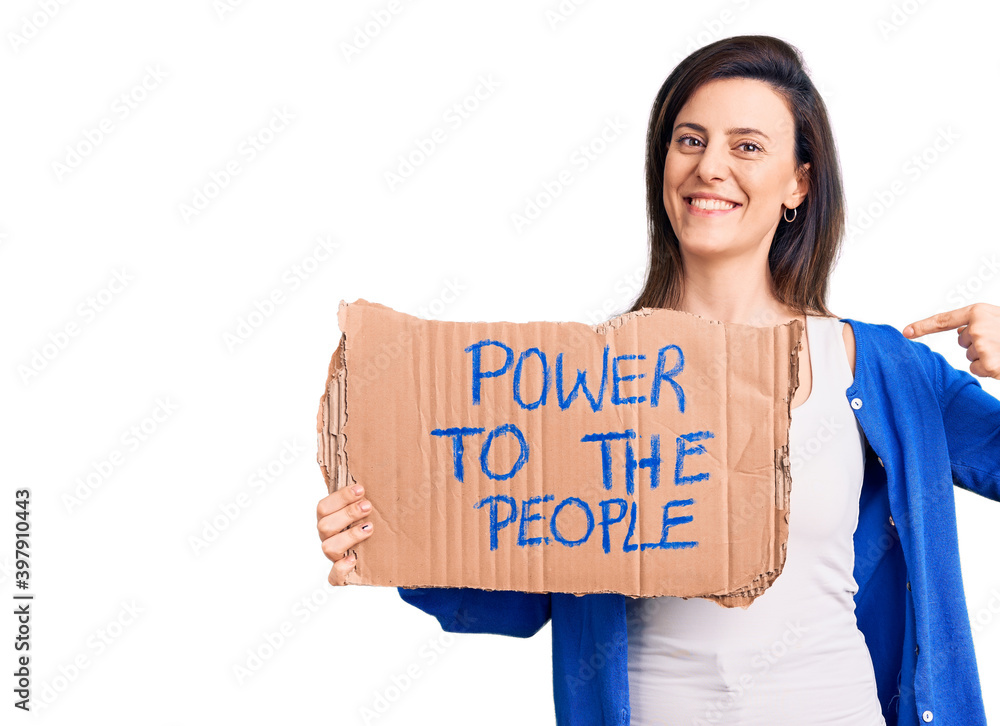 Young beautiful woman holding power to the people banner pointing finger to one self smiling happy and proud Young beautiful woman holding power to the people banner pointing finger to one self smiling happy and proud