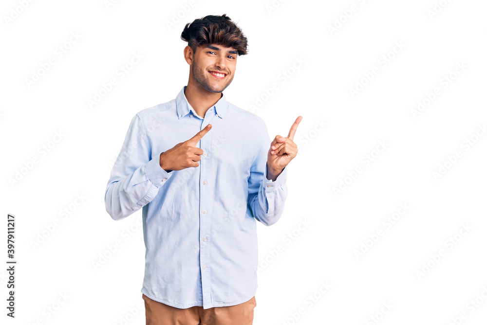 Young hispanic man wearing casual shirt smiling and looking at the camera pointing with two hands and fingers to the side. Young hispanic man wearing casual shirt smiling and looking at the camera pointing with two hands and fingers to the side.