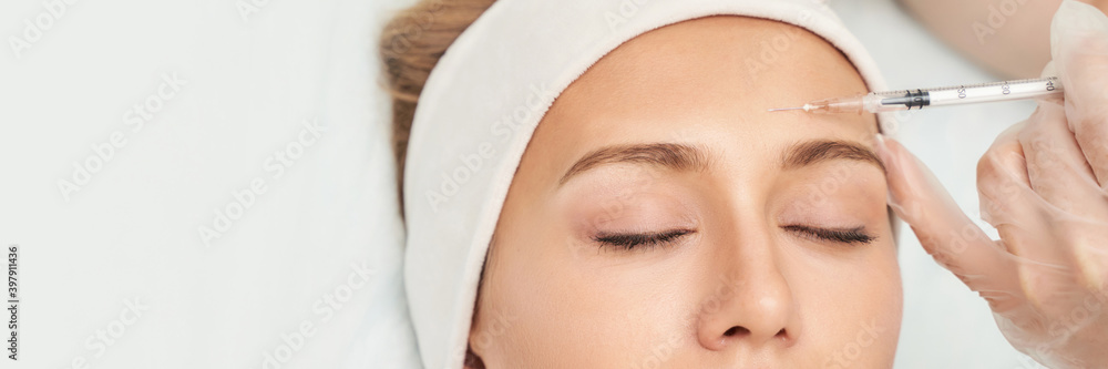 Forehead injection at spa salon. Doctor hands. Closeup. High quality. Pretty female patient. Beauty treatment. Healthy skin procedure. Young woman face. Light background. Plasmolifting rejuvenation