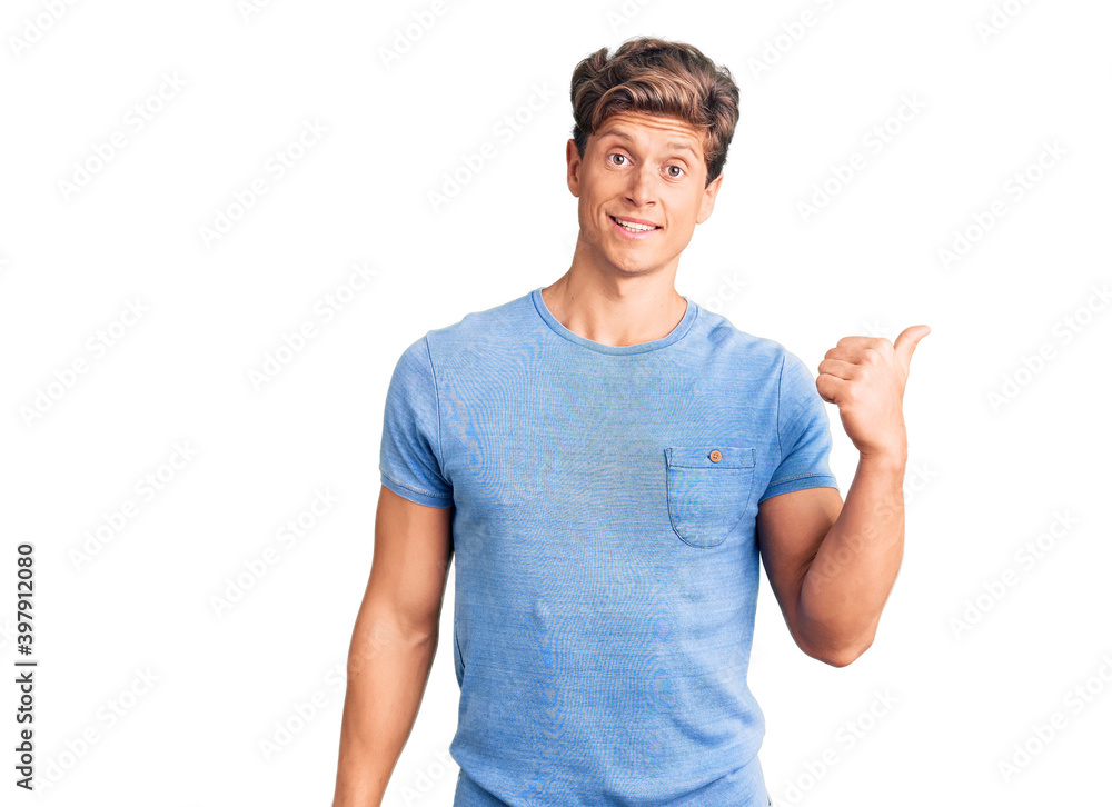 Young handsome man wearing casual clothes smiling with happy face looking and pointing to the side with thumb up. Young handsome man wearing casual clothes smiling with happy face looking and pointing to the side with thumb up.
