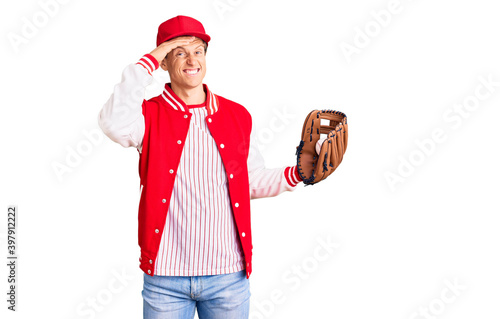 Young handsome man wearing baseball uniform holding golve and ball stressed and frustrated with hand on head, surprised and angry face photo