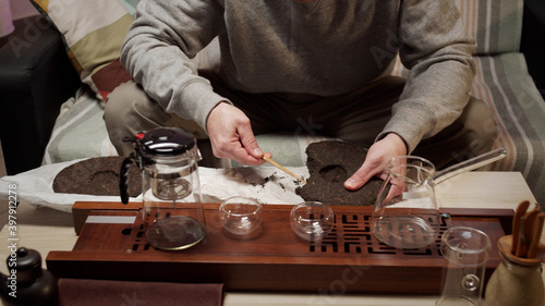 The hands of a tea master pick out pieces from a da hung pao tea bar to enjoy the rich taste of a traditional vietnamese drink.