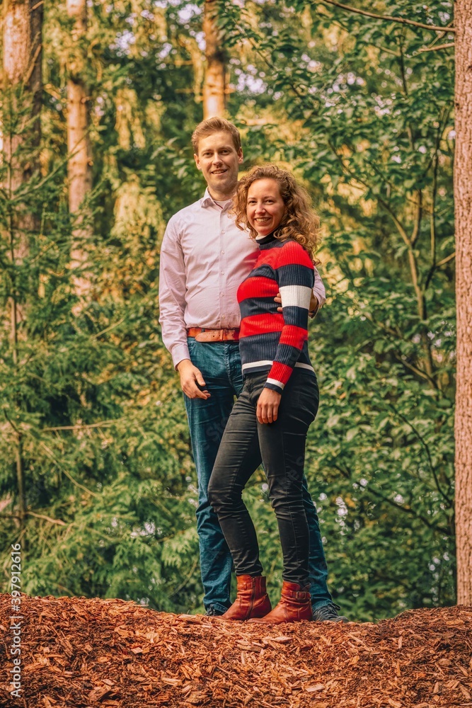 Happy young couple outdoors on beautiful autumn day. standing on a mountain of bark in the forest