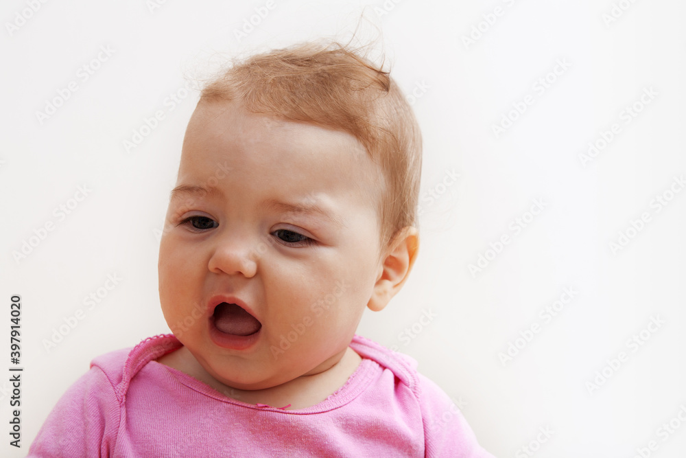 Dissatisfied baby of the first year of life on a white background