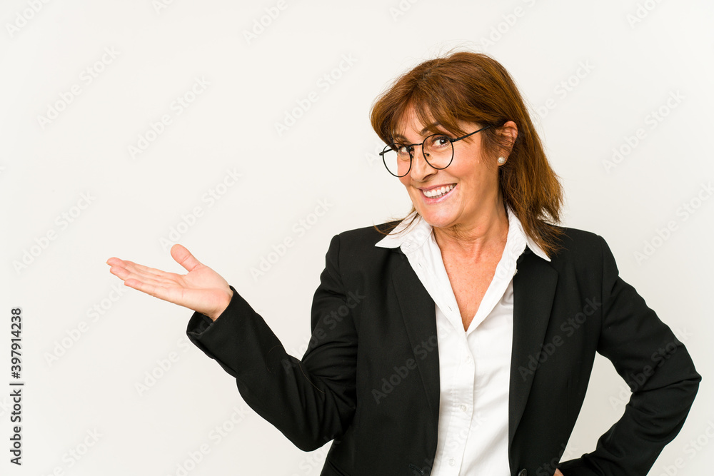 Middle age caucasian business woman isolated showing a copy space on a palm and holding another hand on waist. Middle age caucasian business woman isolated showing a copy space on a palm and holding another hand on waist.