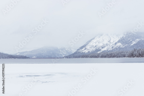 Frozen Mountain Lake Covered in Snow on Cloudy Day in Winter
