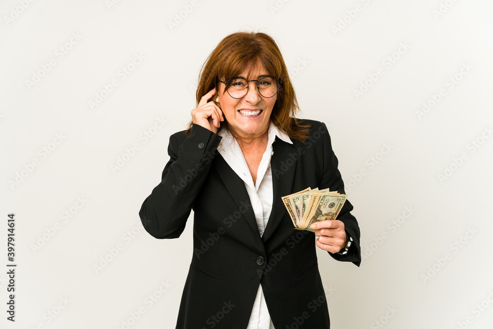 Middle age caucasian business woman holding banknotes isolated covering ears with hands. Middle age caucasian business woman holding banknotes isolated covering ears with hands.