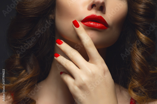 Beautiful young model with red lips and red manicure hild white sheet.