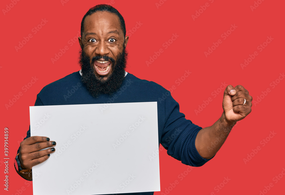Young african american man holding blank empty banner screaming proud, celebrating victory and success very excited with raised arms Young african american man holding blank empty banner screaming proud, celebrating victory and success very excited with raised arms