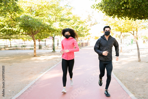 Full length of a fit couple with face masks running together outdoors