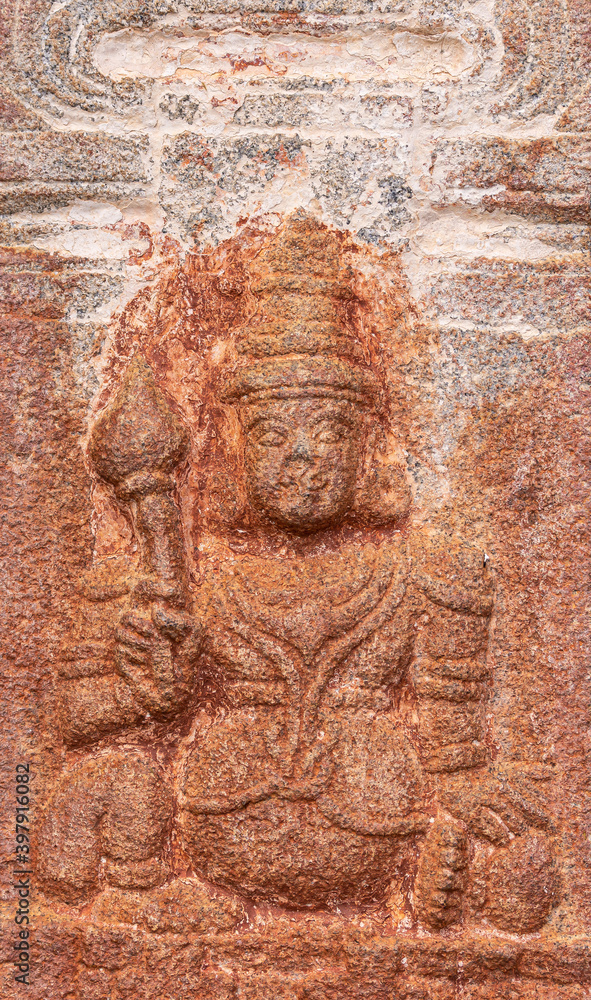 Hampi, Karnataka, India - November 4, 2013: Virupaksha Temple complex. Closeup of red stone mural sculpture of Dwarapalaka in sitting position.