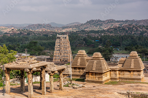 Hampi, Karnataka, India - November 4, 2013: Virupaksha Temple complex. Aarial view on brown-yellow stone Shiva Vimanam and other buldings with green landscape in back. photo