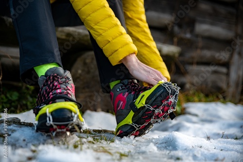 Bild auf Leinwand Hands female mountaineers wear crampons for boots before climbing the mountains in winter