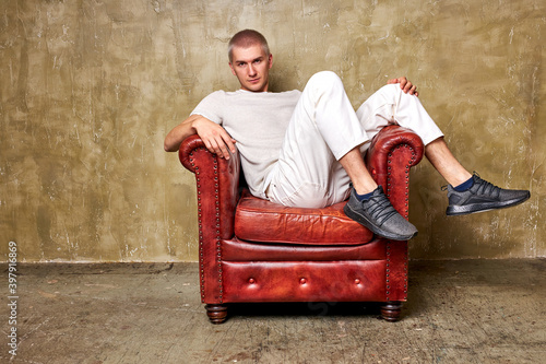 Fotografie portrait of young serious caucasian man in white casual wear sitting on leather
