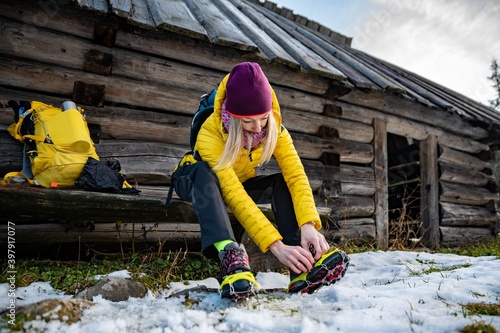 Beautiful female tourist in an alpine resort wears crampons before climbing the top.