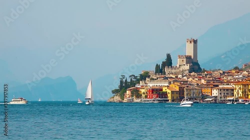 Malcesine, Lake Garda, Italy. Picturesque landscape of the lake with ancient small village town on the banks among the Alps Mountains. Ships and jachts on the water photo