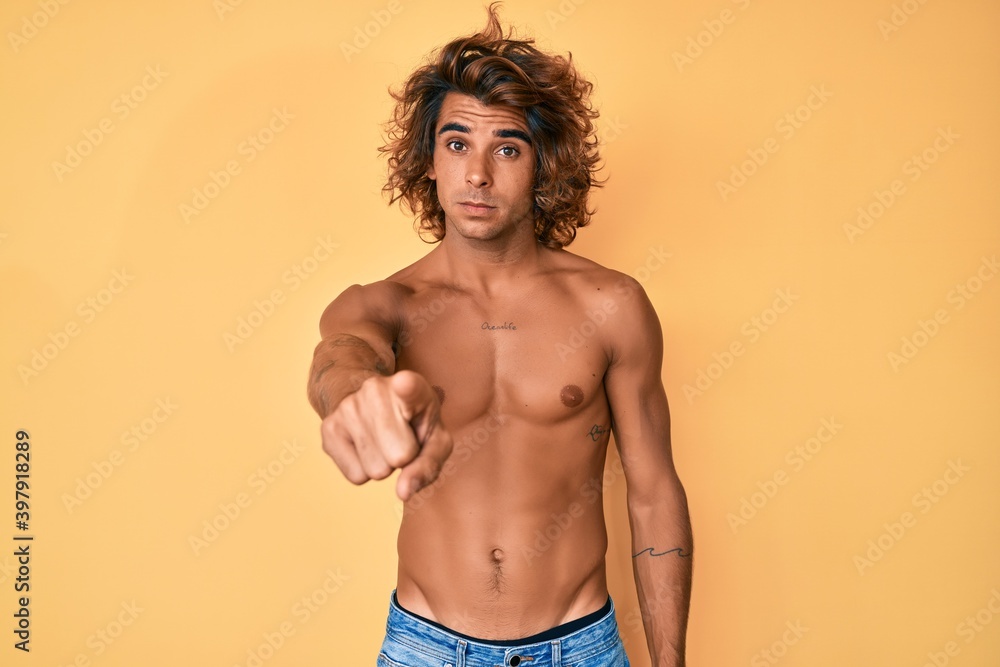 Young hispanic man standing shirtless pointing displeased and frustrated to the camera, angry and furious with you