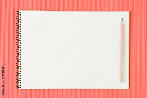 notebook with pencil on pink color background