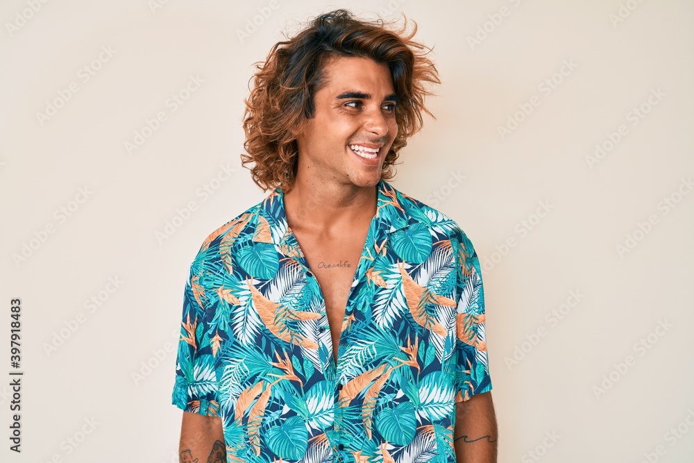 Young hispanic man wearing summer shirt looking away to side with smile on face, natural expression. laughing confident. Young hispanic man wearing summer shirt looking away to side with smile on face, natural expression. laughing confident.