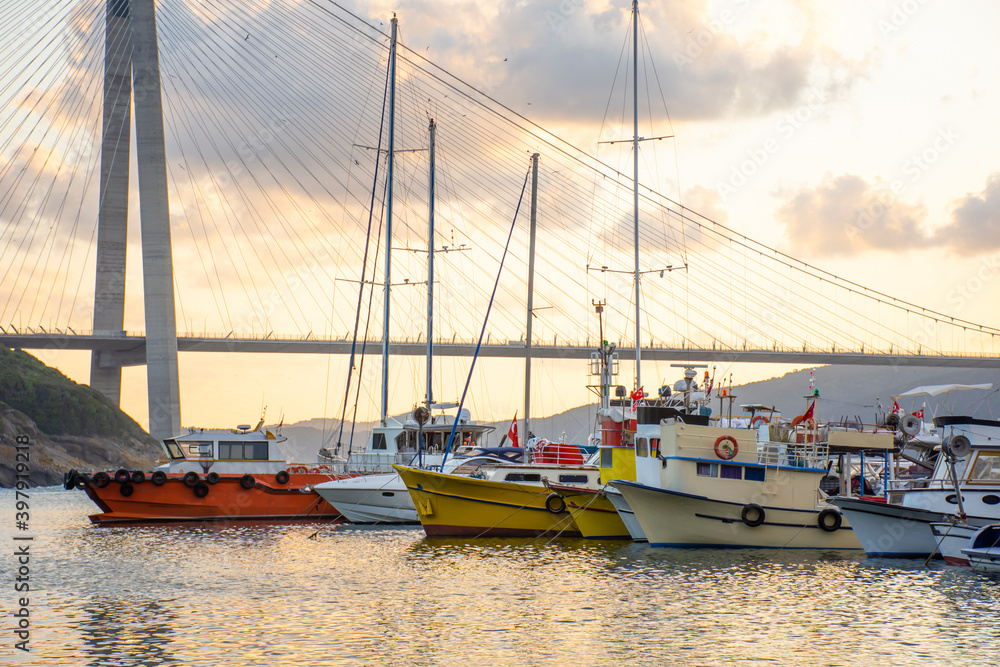 Panoramic view of the Yavuz Sultan Selim Bridge in Istanbul, Turkey. Sunset time. Small port with yachts and fishing boats in front of Third Istanbul bridge. Panoramic view of the Yavuz Sultan Selim Bridge in Istanbul, Turkey. Sunset time. Small port with yachts and fishing boats in front of Third Istanbul bridge.