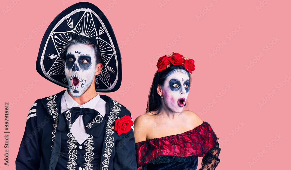 Young couple wearing mexican day of the dead costume over background angry and mad screaming frustrated and furious, shouting with anger. rage and aggressive concept. Young couple wearing mexican day of the dead costume over background angry and mad screaming frustrated and furious, shouting with anger. rage and aggressive concept.