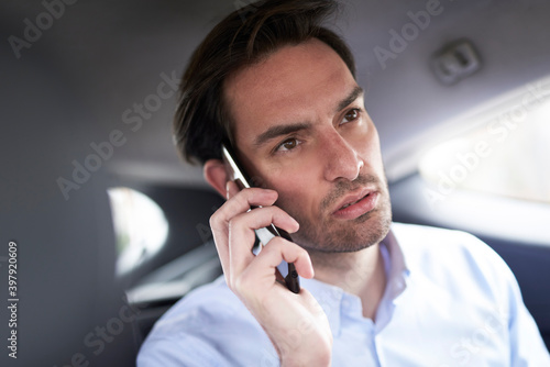 Young business man talking on his phone in the taxi
