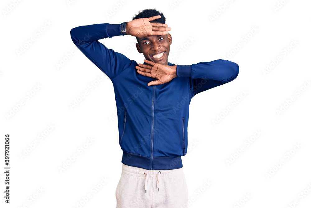 Young african american man wearing sportswear smiling cheerful playing peek a boo with hands showing face. surprised and exited Young african american man wearing sportswear smiling cheerful playing peek a boo with hands showing face. surprised and exited