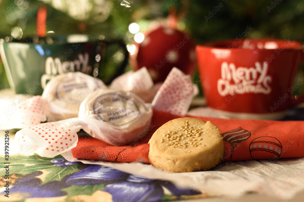 Two Christmas mugs and several homemade polvorones with the Christmas tree in the background.
