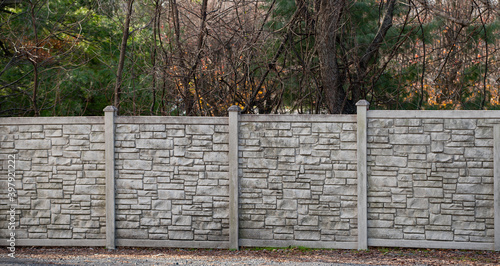 Modern pattern of light stone fence wall with posts in front photo