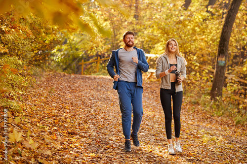 happy couple enjoying jogging on a country road through the beautiful autumn forest, exercise and fitness concept