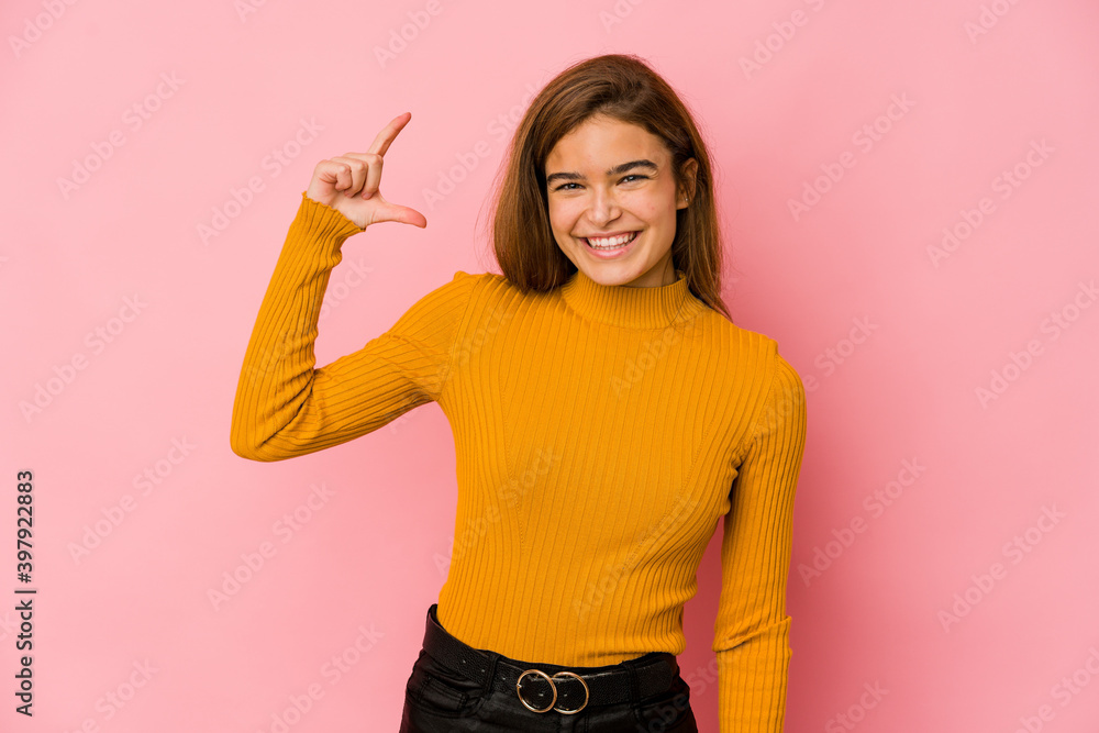Young skinny caucasian teenager girl holding something little with forefingers, smiling and confident. Young skinny caucasian teenager girl holding something little with forefingers, smiling and confident.
