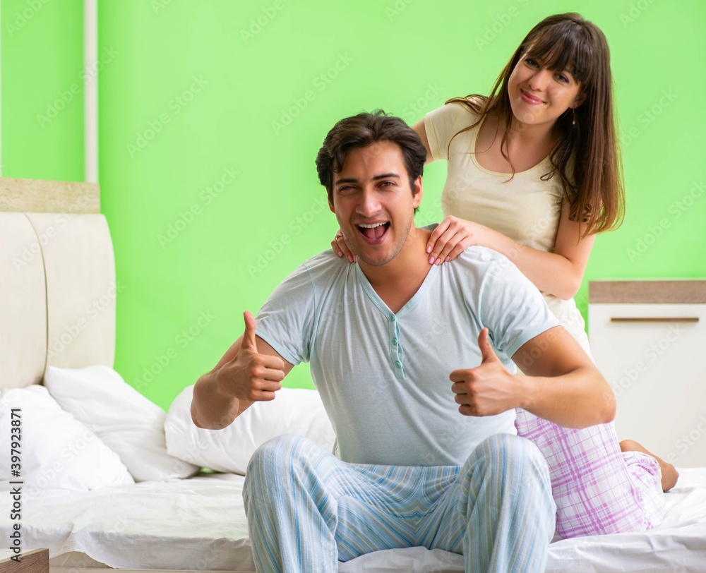 Woman doing massage to her husband in bedroom Woman doing massage to her husband in bedroom