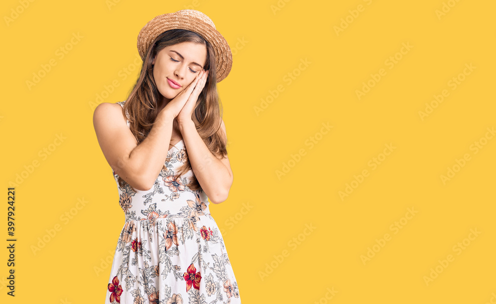 Beautiful caucasian young woman wearing summer hat sleeping tired dreaming and posing with hands together while smiling with closed eyes. Beautiful caucasian young woman wearing summer hat sleeping tired dreaming and posing with hands together while smiling with closed eyes.