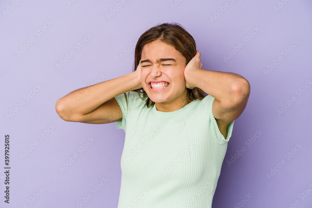 Young skinny caucasian girl teenager on purple background covering ears with hands. Young skinny caucasian girl teenager on purple background covering ears with hands.