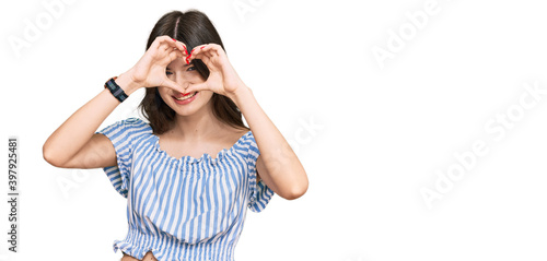 Young beautiful caucasian girl wearing casual clothes doing heart shape with hand and fingers smiling looking through sign
