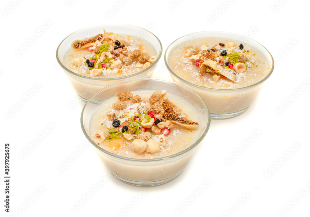 Closeup of traditional Turkish Dessert Asure or Ashura (aka Noah Pudding) in glass bowls isolated on white background. with copy space for text. Closeup of traditional Turkish Dessert Asure or Ashura (aka Noah Pudding) in glass bowls isolated on white background. with copy space for text.