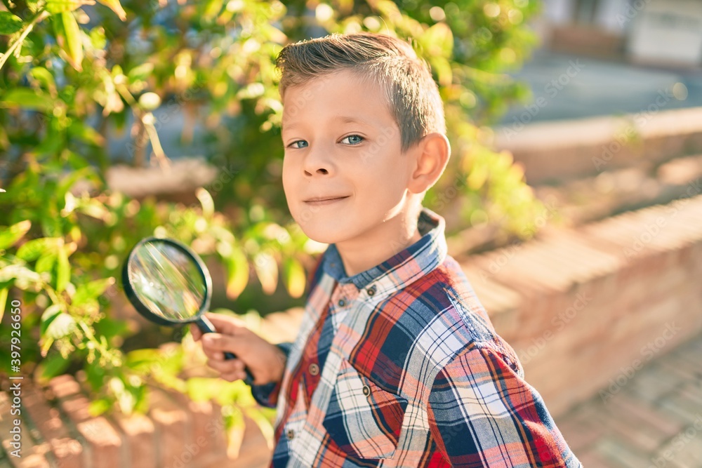 Adorable caucasian explorer boy using magnifying glass at the park. Adorable caucasian explorer boy using magnifying glass at the park.