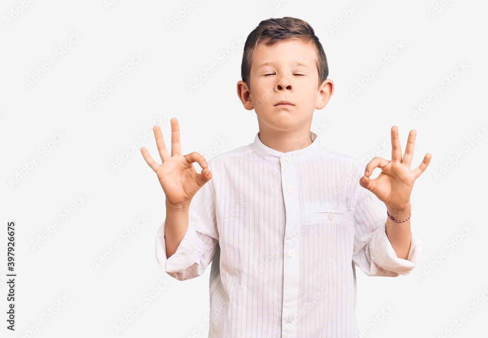 Cute blond kid wearing elegant shirt relaxed and smiling with eyes closed doing meditation gesture with fingers. yoga concept. Cute blond kid wearing elegant shirt relaxed and smiling with eyes closed doing meditation gesture with fingers. yoga concept.