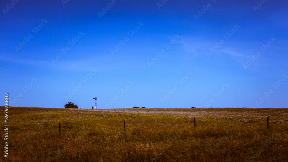 American classic windmill on horizon against blue sky