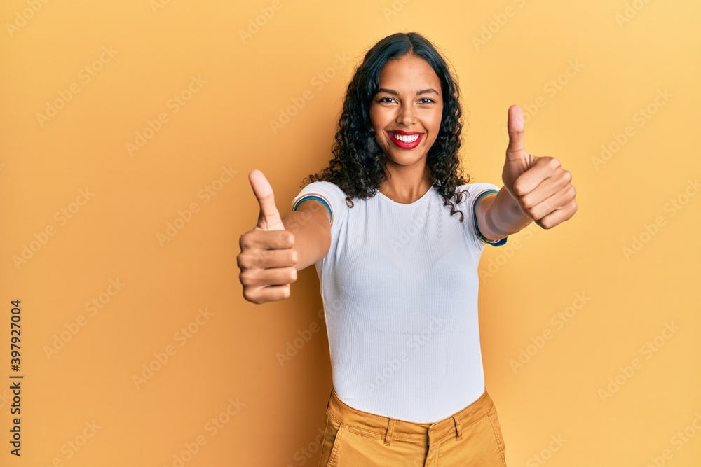 Young african american girl wearing casual clothes approving doing positive gesture with hand, thumbs up smiling and happy for success. winner gesture. Young african american girl wearing casual clothes approving doing positive gesture with hand, thumbs up smiling and happy for success. winner gesture.