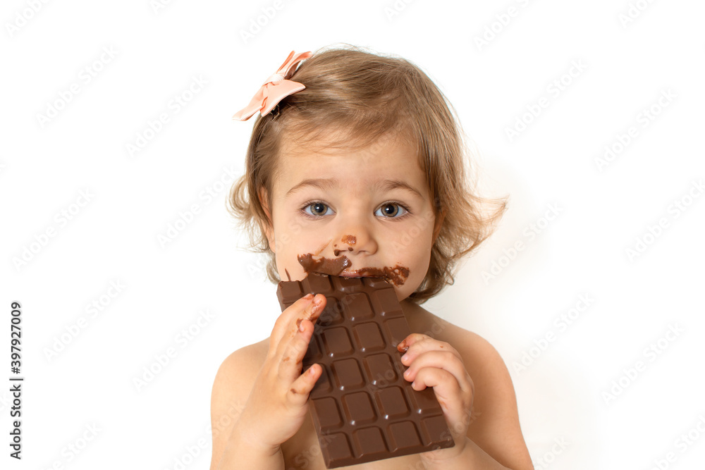 Portrait of adorable small baby girl eating plate of chocolate. Close up of toddler child with dirty funny face. Little cute kid isolated on white background with copy space. Portrait of adorable small baby girl eating plate of chocolate. Close up of toddler child with dirty funny face. Little cute kid isolated on white background with copy space.