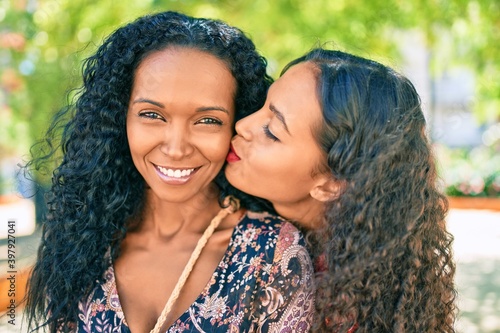 African american mother and daughter smiling happy hugging and kissing at the park.