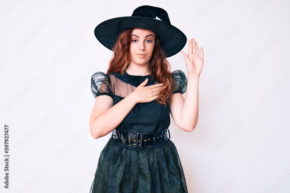 Young beautiful woman wearing witch halloween costume swearing with hand on chest and open palm, making a loyalty promise oath Young beautiful woman wearing witch halloween costume swearing with hand on chest and open palm, making a loyalty promise oath