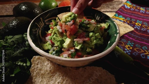 Mexican guacamole with tomato and jalapeno pepper on wooden background