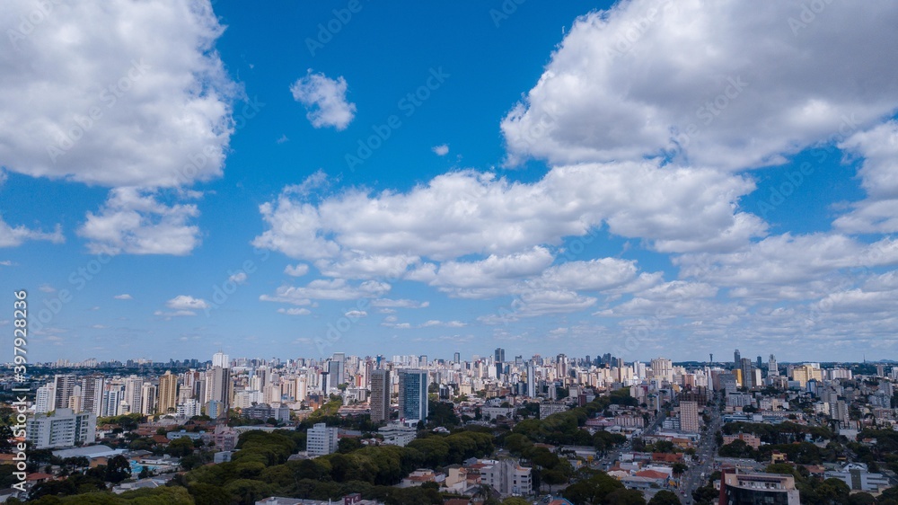 Panoramic drone view of the Alto de XV neighborhood, in the upper third the blue sky with clouds, below and in the background the center of Curitiba, capital of the state of Paraná, located in the sou