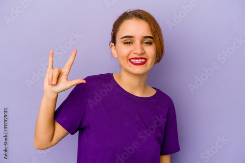 Young arab mixed race woman showing a horns gesture as a revolution concept.