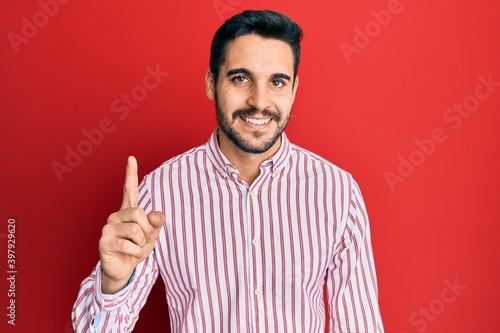 Young hispanic man wearing business shirt smiling with an idea or question pointing finger up with happy face, number one