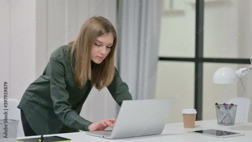 Young Woman Standing while using Laptop at Work Young Woman Standing while using Laptop at Work