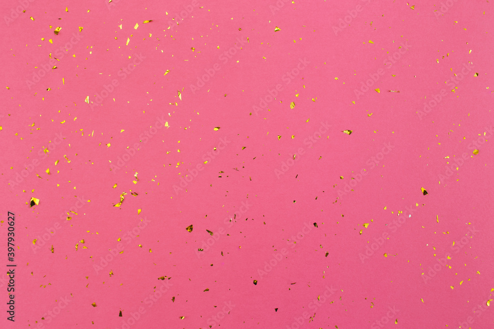 Gold confetti on pink paper background. Festive holiday backdrop. Birthday congratulations Christmas New Year. Valentines Day. Flat lay, top view, copy space.