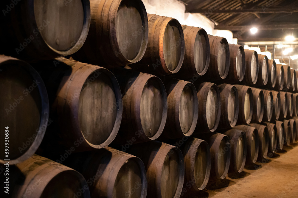 Old porto lodge with rows of oak wooden casks for slow aging of fortified ruby or tawny porto wine in Vila Nova de Gaia, Portugal Old porto lodge with rows of oak wooden casks for slow aging of fortified ruby or tawny porto wine in Vila Nova de Gaia, Portugal
